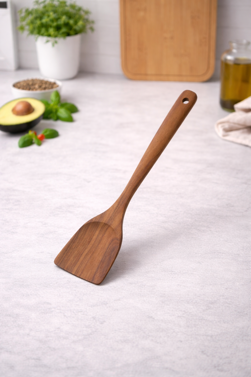 Wooden spatula on a light gray surface with kitchen items in the background
