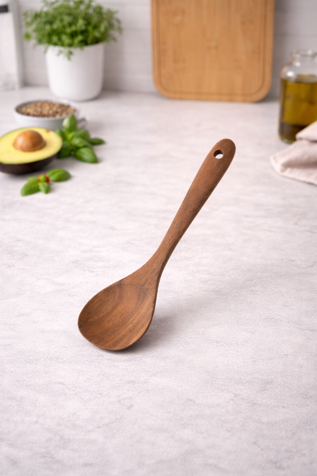 Wooden spoon on a light gray surface with kitchen items in the background